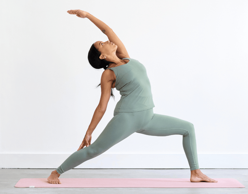 Person practising Reverse Warrior Pose (Viparita Virabhadrasana), with the front knee bent, back leg extended and upper arm reaching overhead as the torso leans back.