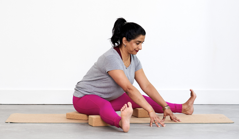 Seated Wide-Legged Forward Fold (Upavistha Konasana) with yoga bricks and blocks supporting the legs.