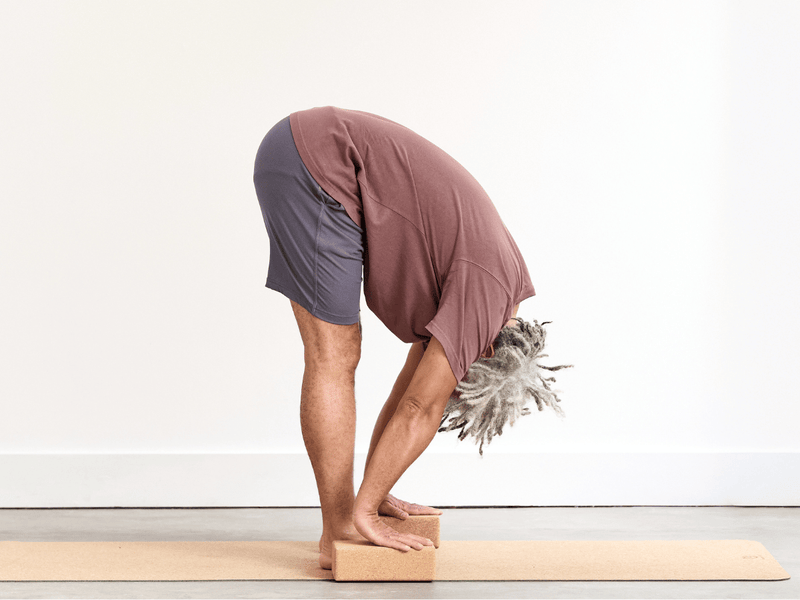 Person practising Standing Forward Fold (Uttanasana), folding forwards from the hips with the upper body releasing towards the legs and the hands reaching towards the floor.