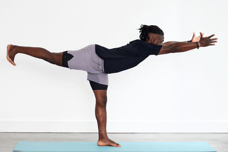 Person practising Warrior III (Virabhadrasana III), balancing on one leg with the opposite leg extended behind and the upper body reaching forwards, creating a long line through the body.
