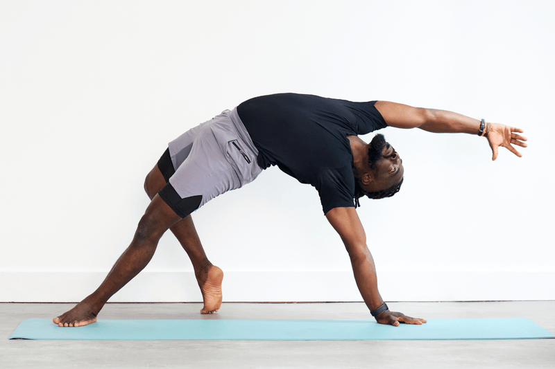 Person practising Wild Thing (Camatkarasana), balancing on one hand and both feet while lifting the hips and reaching the opposite arm overhead in a backbend.