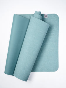 Teal yoga mat partially rolled with textured design, top view on white background