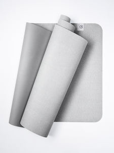 Gray textured yoga mat partially rolled with visible Liforme brand logo on white background, eco-friendly high-grip yoga accessory shot from side angle.