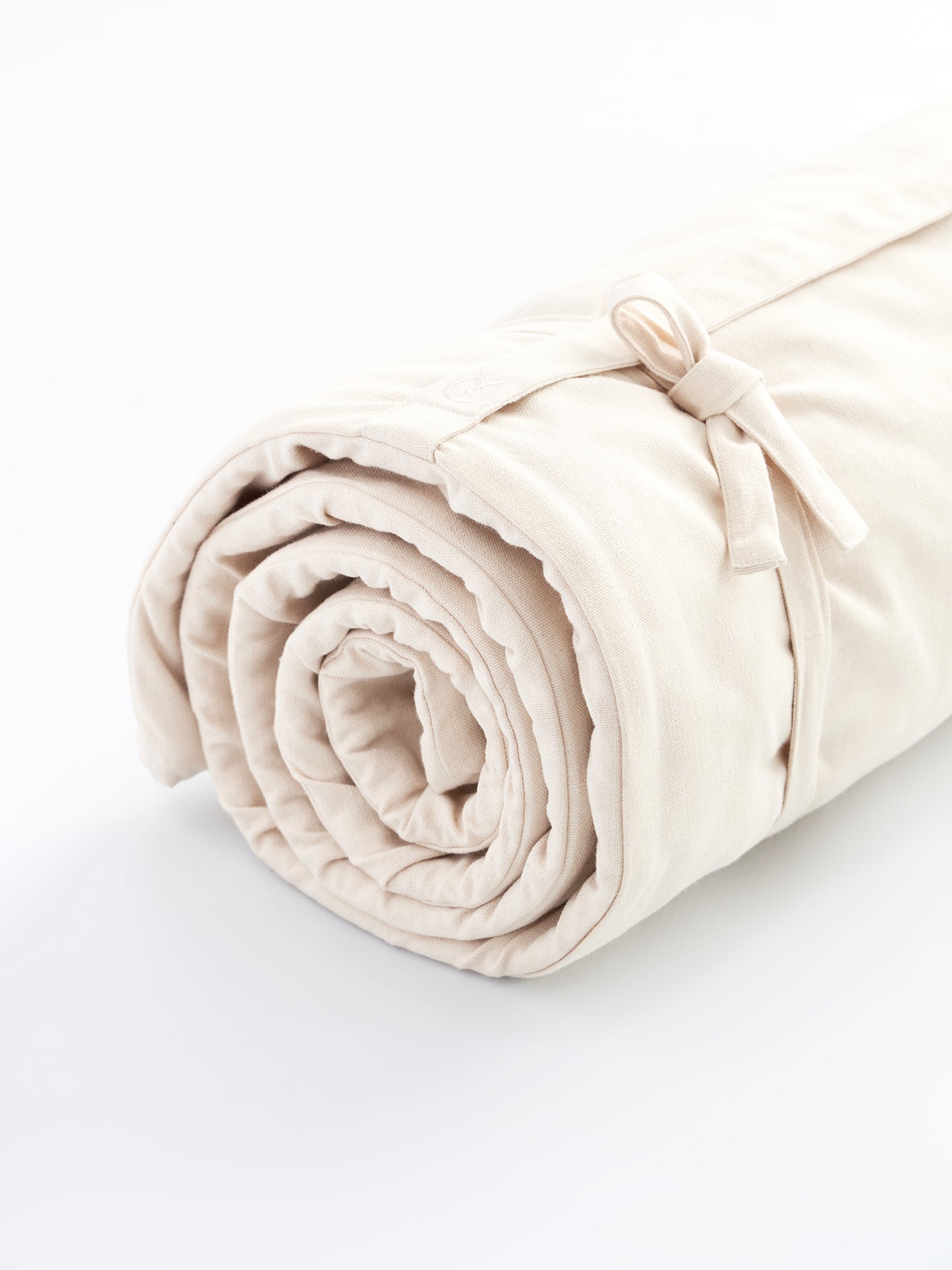 Beige rolled yoga mat side view with strap detail on white background