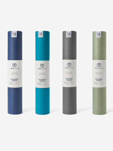 YogaMatters Eco Everyday Yoga Mat collection, front view of rolled mats in navy blue, teal, grey, and green colors on white background.