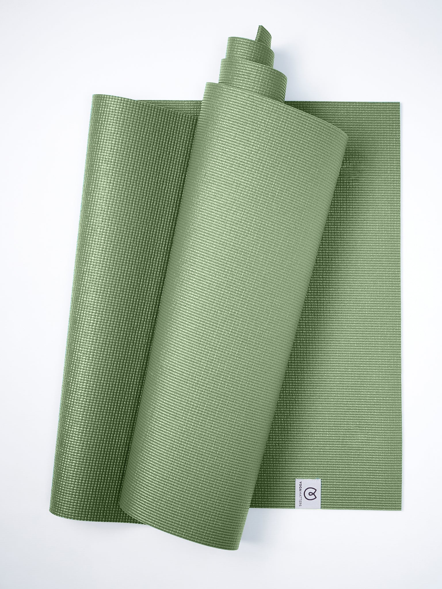 Green textured yoga mat partially rolled up on a white background, top view, with visible brand logo on the corner.
