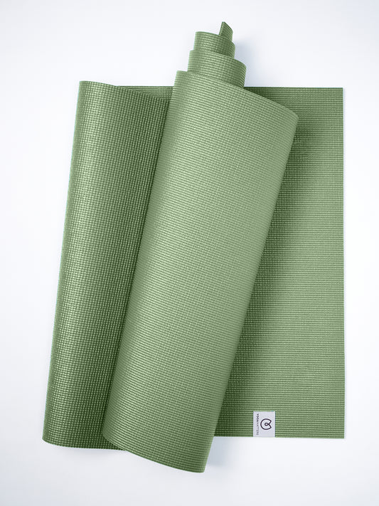 Green textured yoga mat partially rolled with visible brand logo on white background, top view, non-slip surface, exercise equipment, fitness accessory, wellness and yoga practice, durable material.