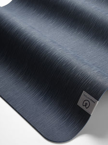 Close-up side view of a textured navy blue Lululemon yoga mat with visible logo.