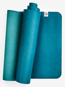 Teal textured yoga mat partly unrolled displaying the brand logo, front view on white background.