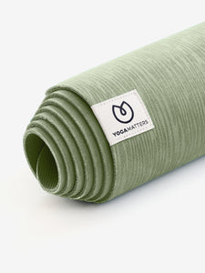 Yogamatters green yoga mat rolled up side view with textured surface and brand label visible on white background