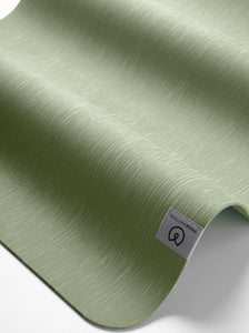 Green textured yoga mat displayed semi-rolled from the side with visible brand label, premium non-slip exercise mat for fitness and wellness.