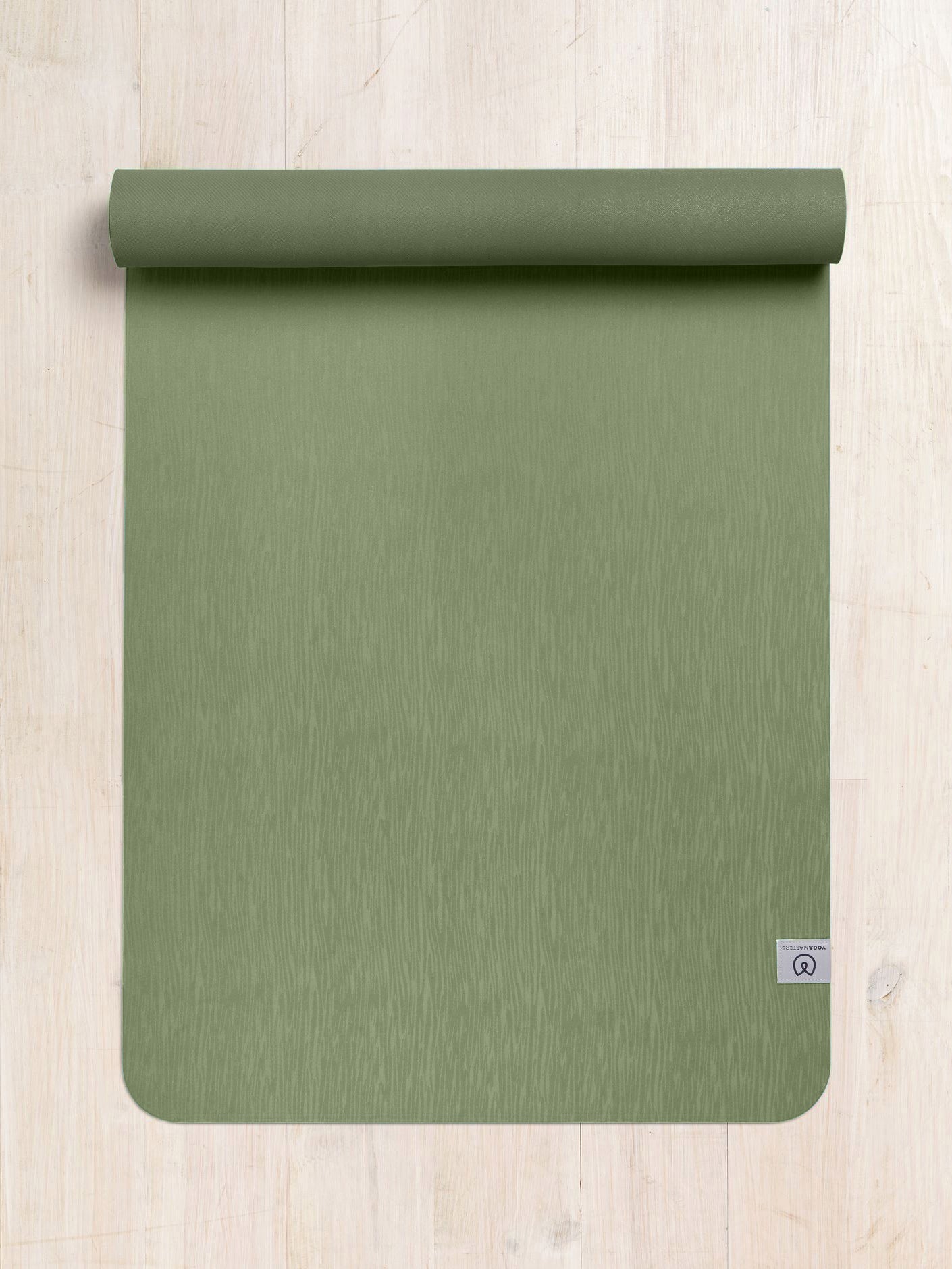 Olive green premium yoga mat rolled halfway with visible texture and brand logo, eco-friendly non-slip exercise mat photographed from overhead on a wooden floor background.