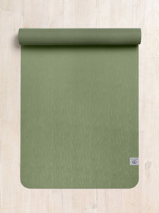 Green textured yoga mat by Lululemon partially rolled up on a wooden floor viewed from the front.