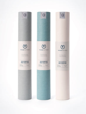 Yogamatters Eco Everyday Rise Yoga Mats, three rolled mats standing upright in grey, blue, and beige colors, isolated on white background.