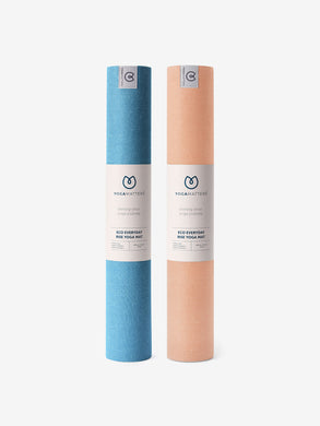 Two rolled up Yogamatters Eco Everyday Rise yoga mats, one in blue and the other in coral, standing upright with visible brand labels, on a white background.