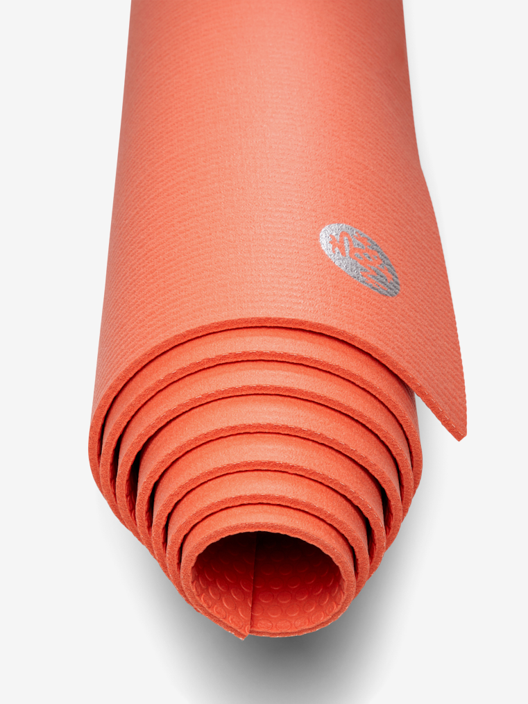 Coral yoga mat rolled up with textured surface and visible brand logo, shot from above.