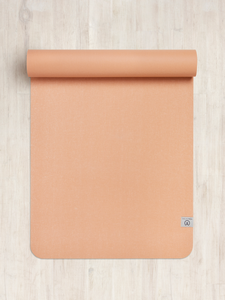 Top-down view of a partially rolled peach-colored yoga mat on a wooden floor, textured non-slip surface, stylish eco-friendly design, fitness and wellness accessory.