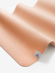 Peach colored Lululemon yoga mat, close-up side shot, textured non-slip surface, rolled eco-friendly design, fitness and exercise accessory