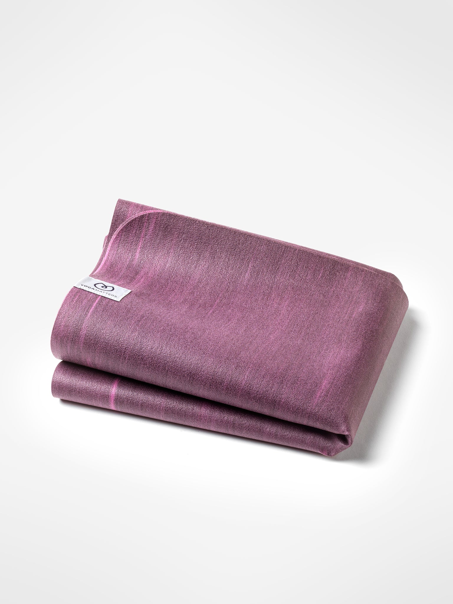 Rolled purple yoga mat with textured surface, visible brand logo on tag, photographed from side on white background