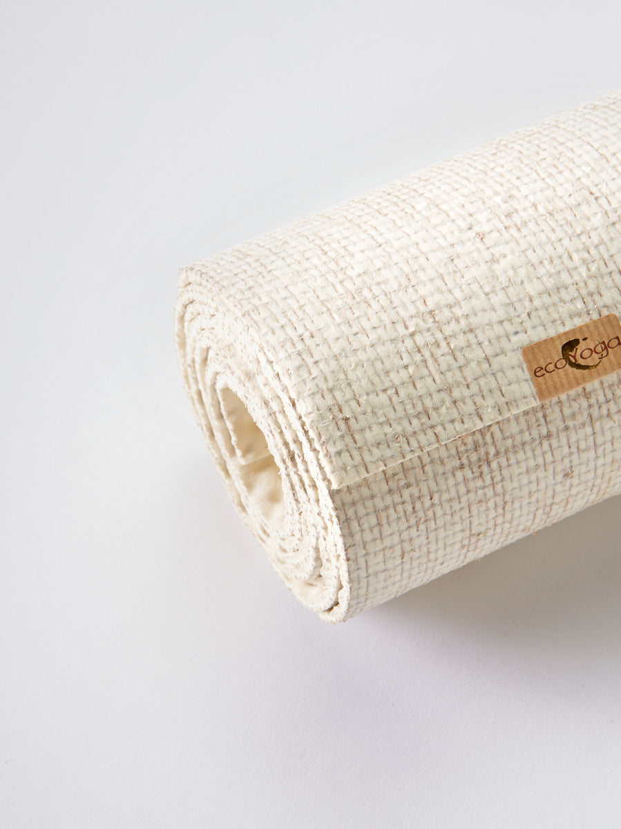 Eco-friendly cream yoga mat by ecoYoga with textured surface, rolled up and shot from the side, displaying brand label.