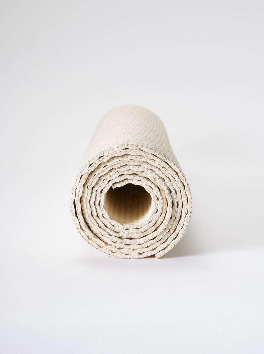 Rolled natural beige yoga mat from front view with textured surface on white background