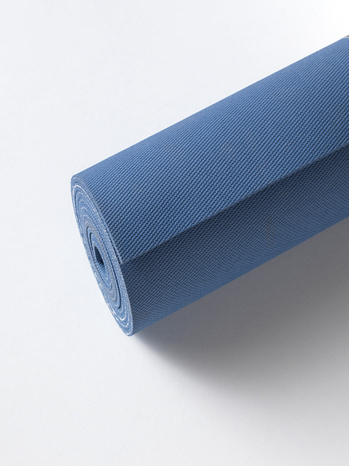 Blue textured yoga mat rolled up on a light background, close-up side view, no visible brand.