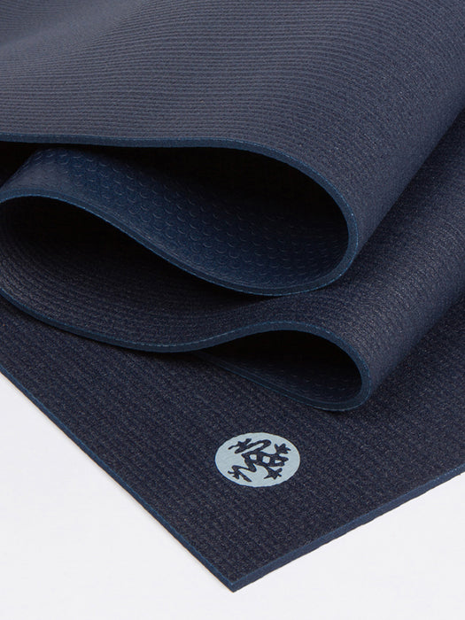 Navy blue textured yoga mat partially unrolled with visible brand logo, non-slip surface, studio shot from side angle for health and wellness equipment.